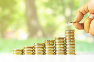 hand placing coin on highest stack, coins stacked in upward results trend