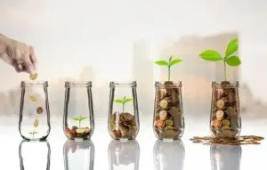 hand placing coins into jar, series of jars in increasing trend with coins and plant growth