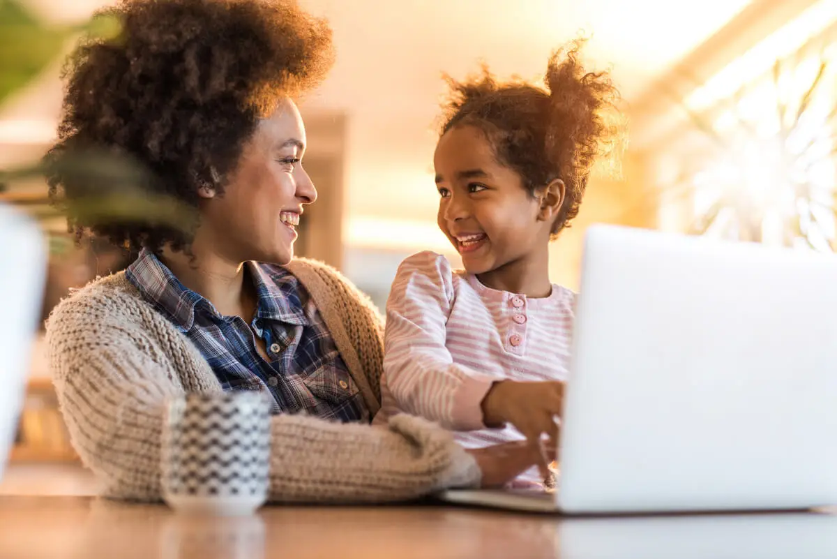 mother and daughter smiling, using laptop