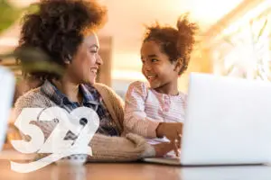 Mother and daughter smiling, using laptop, 529 logo